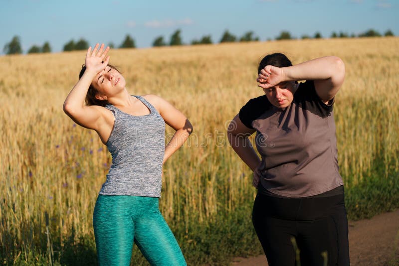 Vrouwen die zweet en rust na openluchtjogging afvegen stock afbeeldingen Vrouwen die zweet en rust na openluchtjogging afvegen stock afbeeldingen
