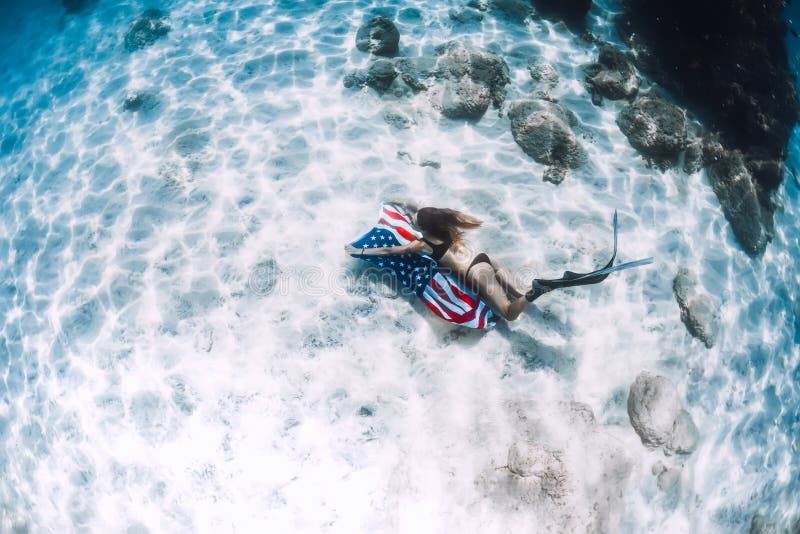 Vrouwen freediver glijdende bewegingen over zandige overzeese bodem met de vlag van Verenigde Staten stock afbeeldingen Vrouwen freediver glijdende bewegingen over zandige overzeese bodem met de vlag van Verenigde Staten stock afbeeldingen