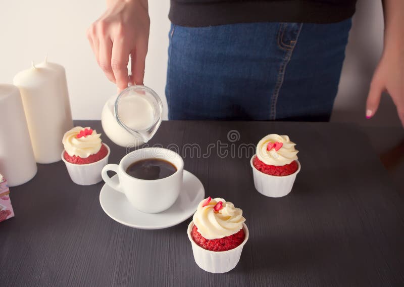 Vrouwen gietende melk op kop van koffie Drie cupcakes met heerlijke room met harten royalty-vrije stock fotografie Vrouwen gietende melk op kop van koffie Drie cupcakes met heerlijke room met harten royalty-vrije stock fotografie