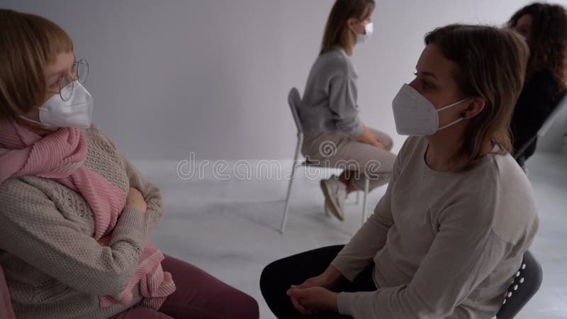 Vrouwen van verschillende leeftijden die maskers dragen ontmoeten elkaar in een therapeutische psychologische groep tijdens de pan