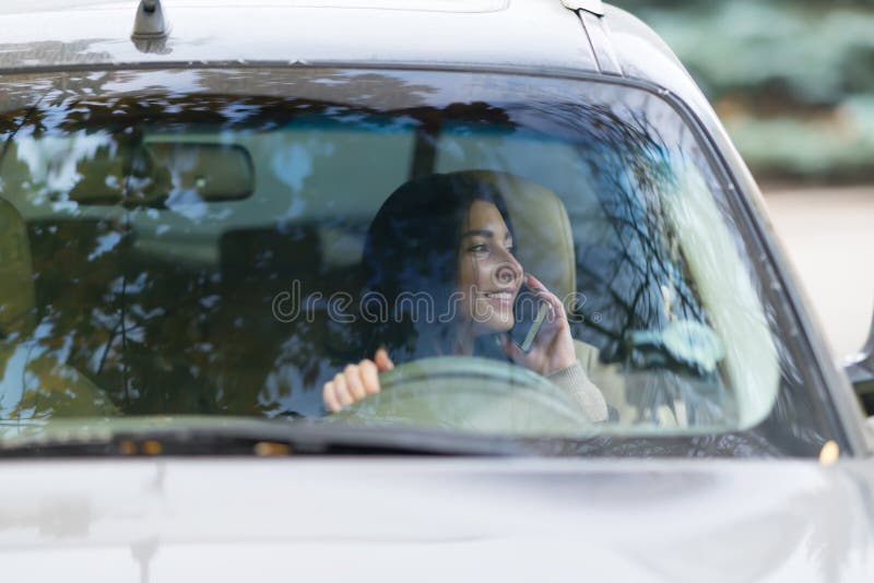 Vrouwenbestuurder die op haar mobiele telefoon spreken stock foto Vrouwenbestuurder die op haar mobiele telefoon spreken stock foto