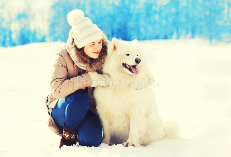 Vrouweneigenaar die witte Samoyed-hond in de winter koesteren royalty-vrije stock foto Vrouweneigenaar die witte Samoyed-hond in de winter koesteren royalty-vrije stock foto