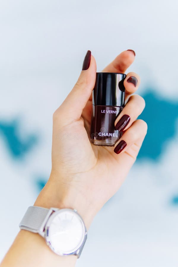 Vrouwenhand die een Fles van Chanel Rouge Noir Nail Polish houden stock fotografie Vrouwenhand die een Fles van Chanel Rouge Noir Nail Polish houden stock fotografie