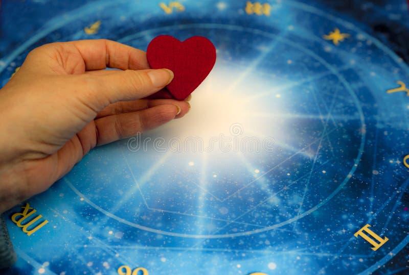 Vrouwenhand die een rood hart over blauwe horoscoop zoals astrologie, dierenriem en liefdeconcept houden royalty-vrije stock afbeelding Vrouwenhand die een rood hart over blauwe horoscoop zoals astrologie, dierenriem en liefdeconcept houden royalty-vrije stock afbeelding