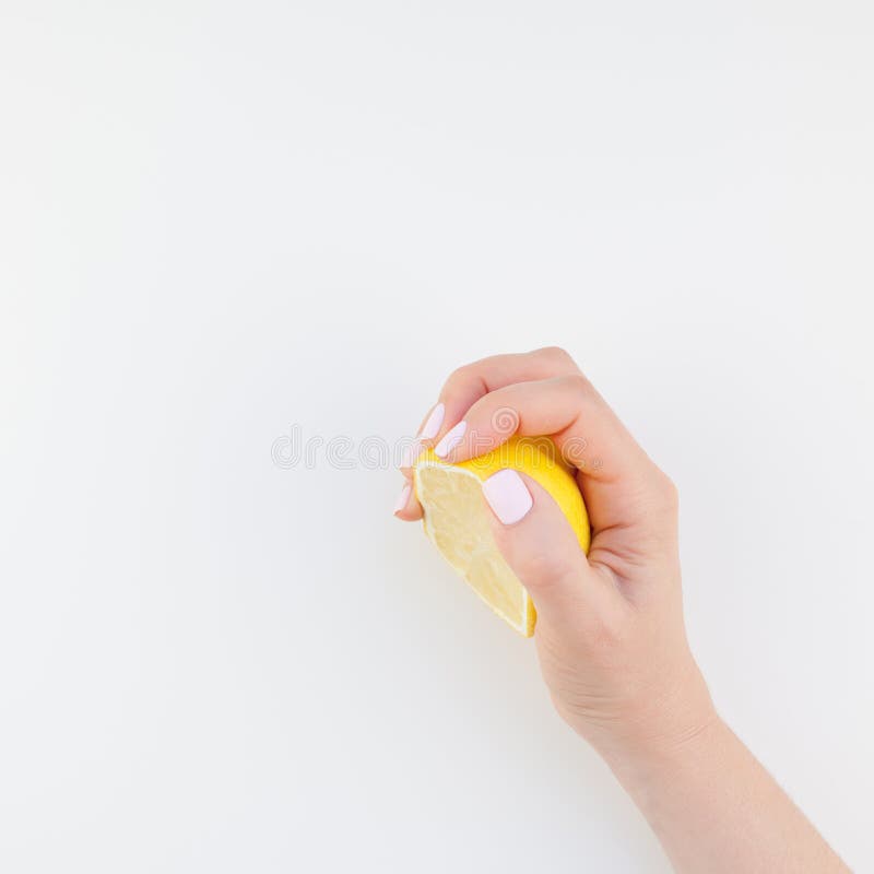 Woman hand with pastel manicure polish holding a half of lemon on white background copy space minimalism style. Square Template for feminine social media. Healthy eating concept. Woman hand with pastel manicure polish holding a half of lemon on white background copy space minimalism style. Square Template for feminine social media. Healthy eating concept