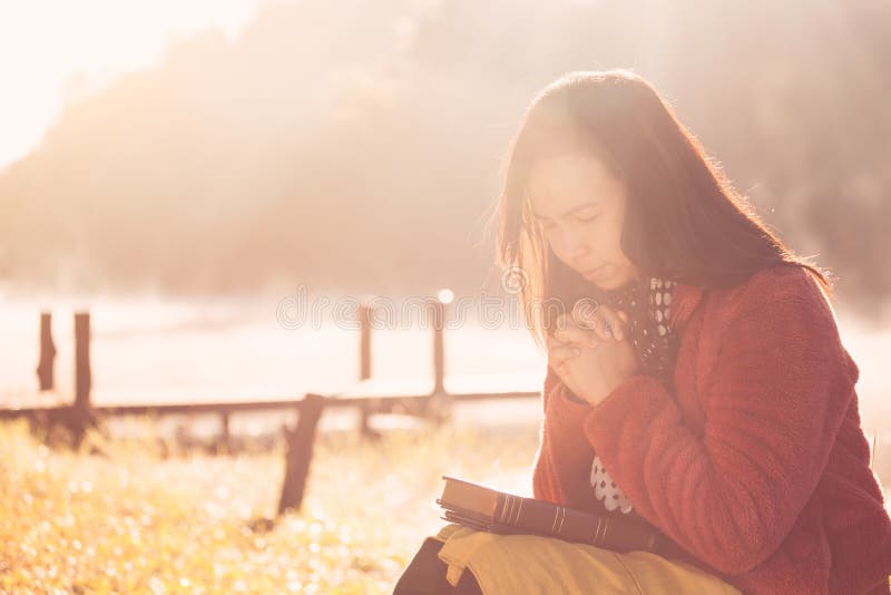 Vrouwenhanden in gebed op een Heilige Bijbel voor geloof worden gevouwen dat