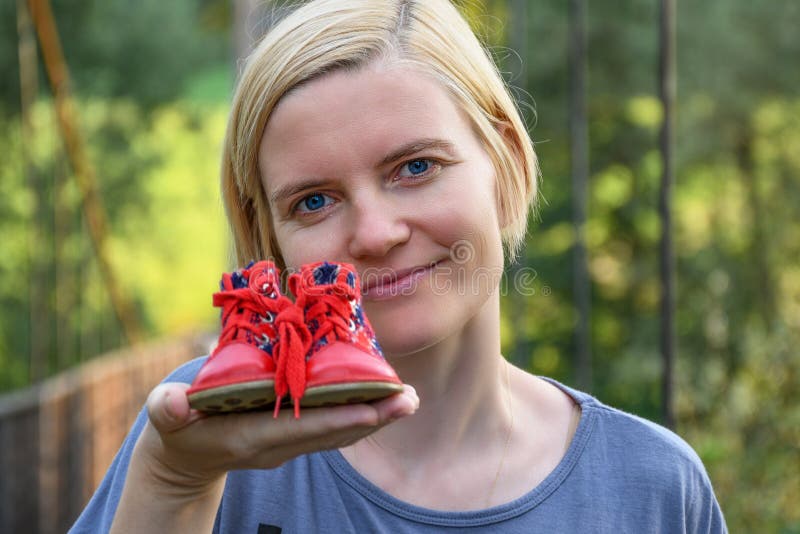 Vrouwenholding in schoenen van één de uitgebreide wapen kleine rode baby royalty-vrije stock foto's Vrouwenholding in schoenen van één de uitgebreide wapen kleine rode baby royalty-vrije stock foto's