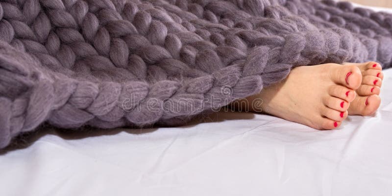 Vrouwenvoeten onder grijze merinos wollen plaid Slaap onder een warme gebreide deken royalty-vrije stock foto Vrouwenvoeten onder grijze merinos wollen plaid Slaap onder een warme gebreide deken royalty-vrije stock foto