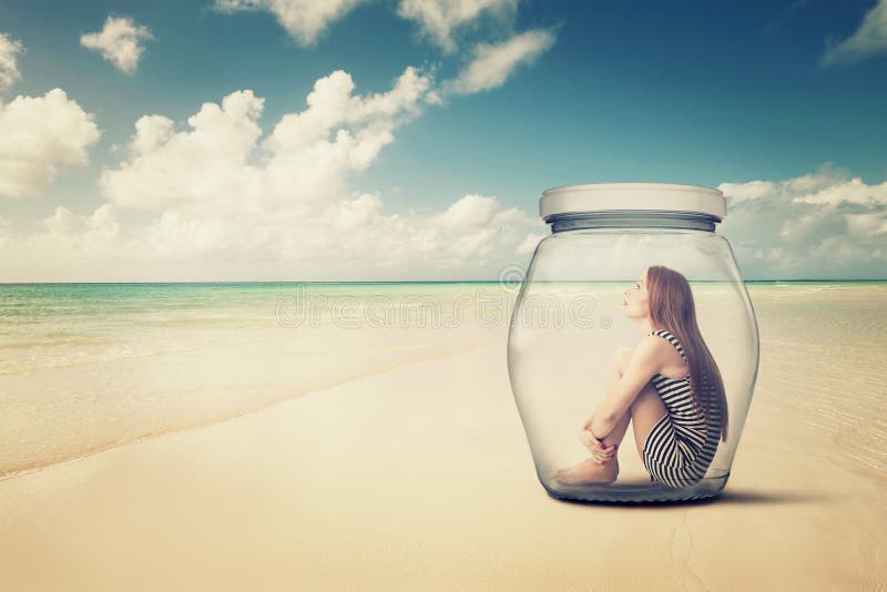Vrouwenzitting in een glaskruik op een strand die de oceaanmening bekijken