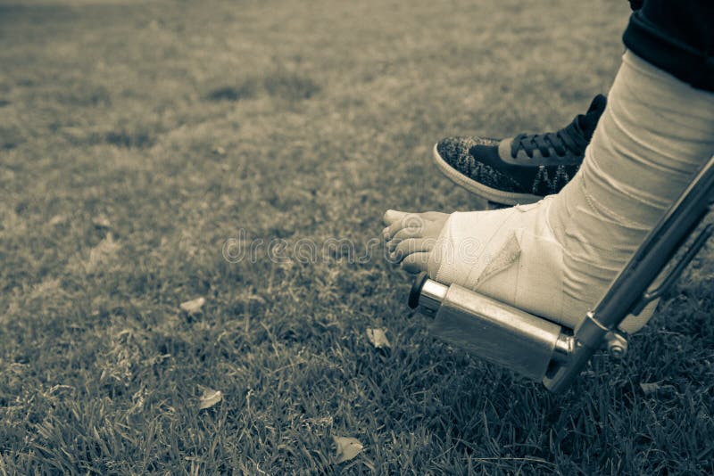 Vu de au-dessus des pieds dans un fauteuil roulant Pied avec l'entorse sur le fond d'herbe photo libre de droits Vu de au-dessus des pieds dans un fauteuil roulant Pied avec l'entorse sur le fond d'herbe photo libre de droits