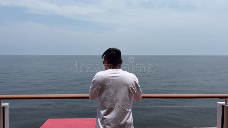 Vue arrière d'un chinois sur un bateau de croisière qui regarde la mer par un beau jour clips vidéos