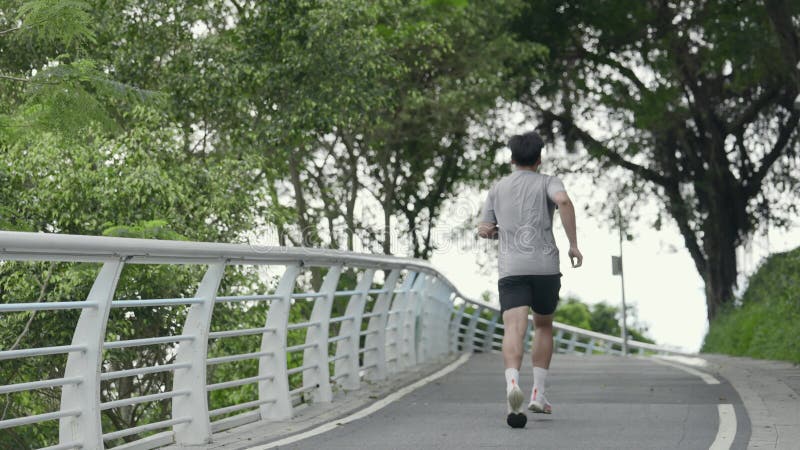 Vue arrière d'un jeune asiatique courant dehors dans le parc banque de vidéos