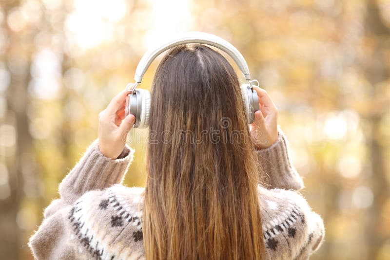 Vue arrière d'une femme en hiver mettant des écouteurs