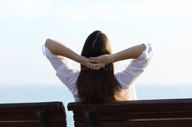 Vue arrière d'une femme se reposant sur la plage images stock