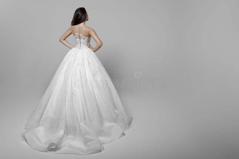 Vue arri?re d'une jeune femme avec de longs cheveux dans la robe l'?pousant blanche, mains sur sa taille, sur un fond blanc photos libres de droits Vue arri?re d'une jeune femme avec de longs cheveux dans la robe l'?pousant blanche, mains sur sa taille, sur un fond blanc photos libres de droits