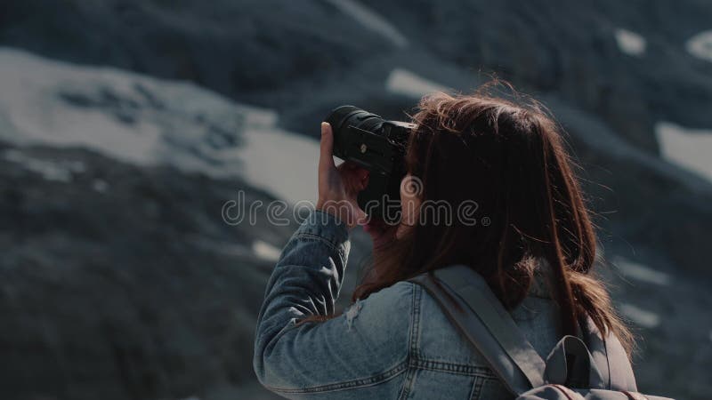 Vue arrière d'une jeune photographe femme prenant des photos dans la nature sauvage avec vue sur la montagne en arrière-plan banque de vidéos