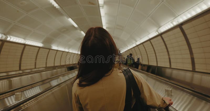 Vue arrière de brunette femme touriste monter l'escalator jusqu'au métro. clips vidéos
