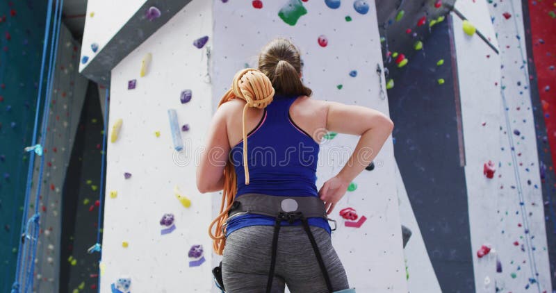 Vue arrière de femme du caucase avec la corde par-dessus son épaule au mur d'escalade intérieure banque de vidéos