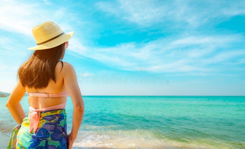Vue arrière de jeune femme asiatique heureuse avec le chapeau de paille détendre et apprécier des vacances à la plage tropicale d photo stock Vue arrière de jeune femme asiatique heureuse avec le chapeau de paille détendre et apprécier des vacances à la plage tropicale d photo stock