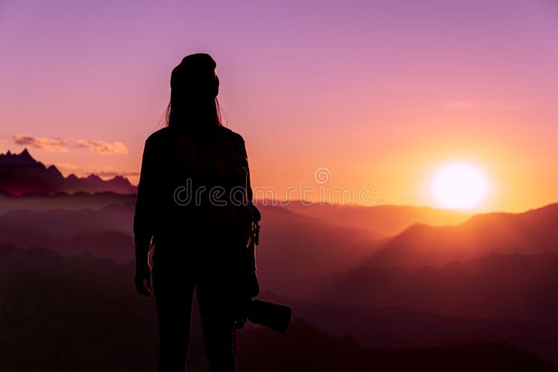 Vue arrière de jeune photographe tenant la caméra avec le coucher du soleil sur le fond naturel de montagne photographie stock Vue arrière de jeune photographe tenant la caméra avec le coucher du soleil sur le fond naturel de montagne photographie stock