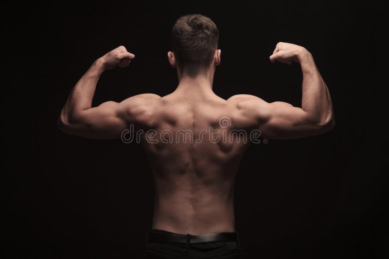 Vue arrière de l'homme musculaire de torse nu posant dans le studio photos stock Vue arrière de l'homme musculaire de torse nu posant dans le studio photos stock