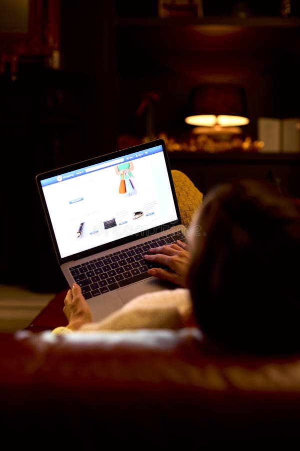 Vue arrière de la femme à la maison assis dans le salon la nuit shopping en ligne