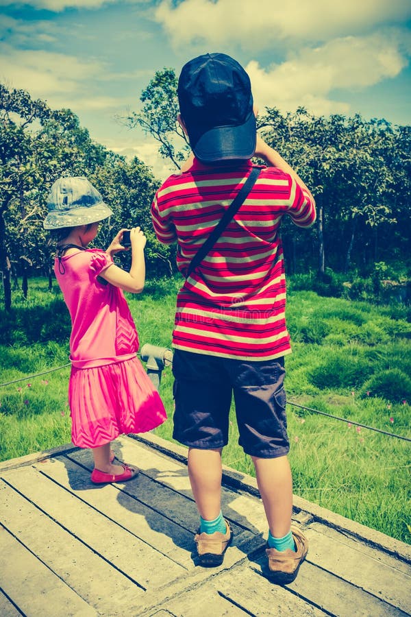 Vue arrière des enfants asiatiques détendant dehors pendant la journée, TR photo libre de droits Vue arrière des enfants asiatiques détendant dehors pendant la journée, TR photo libre de droits