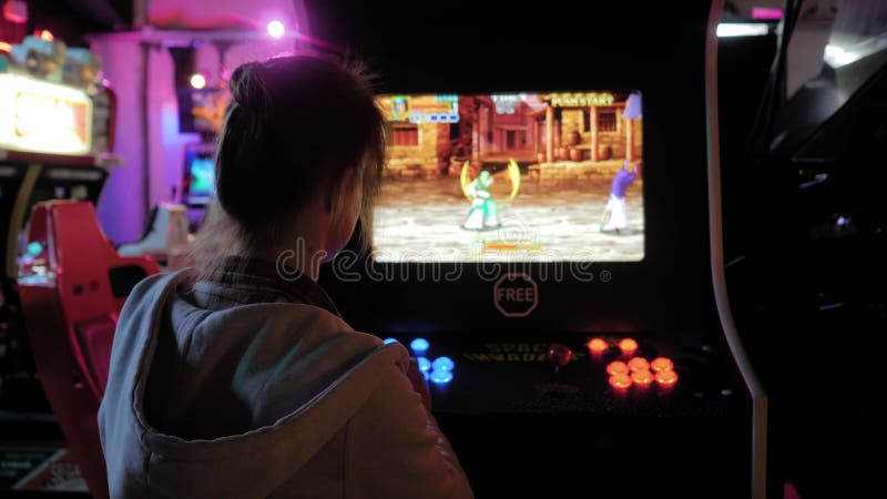 Vue arrière : femme poussant les boutons et jouant jeu arcade banque de vidéos