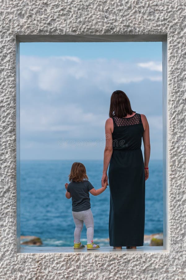Vue arrière sur la mère avec la fille qui restent sur le cadre de marbre et regarder la mer images stock Vue arrière sur la mère avec la fille qui restent sur le cadre de marbre et regarder la mer images stock