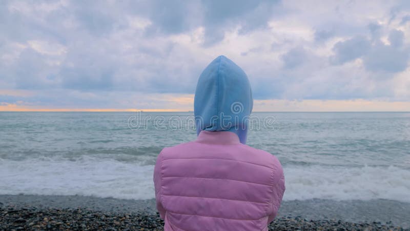 Vue arrière : une femme se tient sur le rivage en regardant les vagues orageuses banque de vidéos
