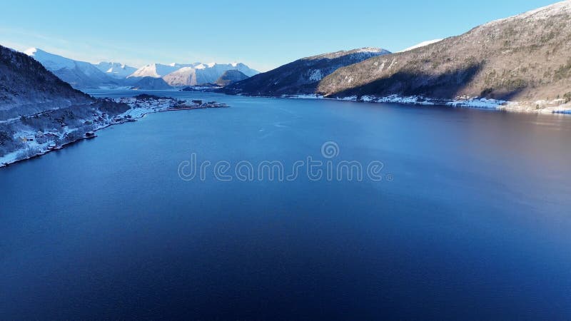Vue aérienne d'un magnifique paysage d'hiver avec des eaux gelées et des montagnes enneigées le matin banque de vidéos