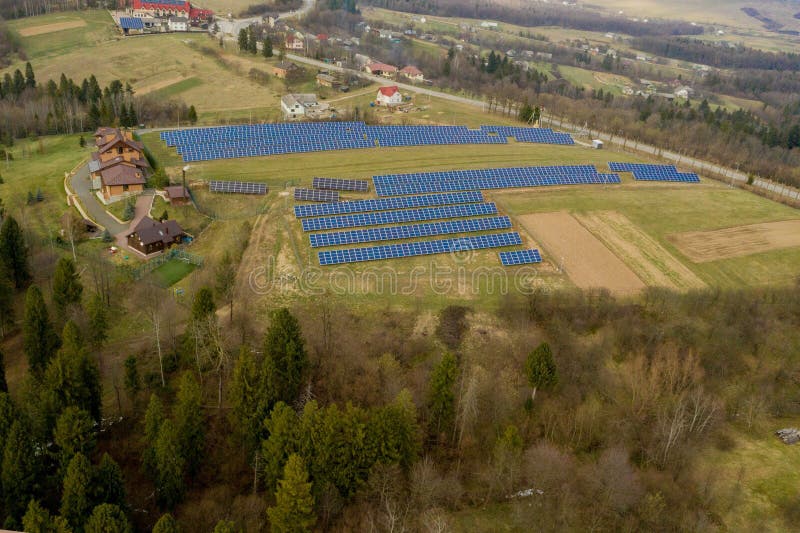Aerial view of large field of solar photo voltaic panels system producing renewable clean energy on green grass background. Aerial view of large field of solar photo voltaic panels system producing renewable clean energy on green grass background.