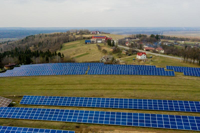 Aerial view of large field of solar photo voltaic panels system producing renewable clean energy on green grass background. Aerial view of large field of solar photo voltaic panels system producing renewable clean energy on green grass background.