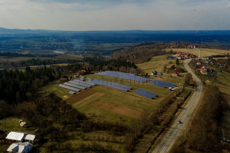 Aerial view of large field of solar photo voltaic panels system producing renewable clean energy on green grass background. Aerial view of large field of solar photo voltaic panels system producing renewable clean energy on green grass background.