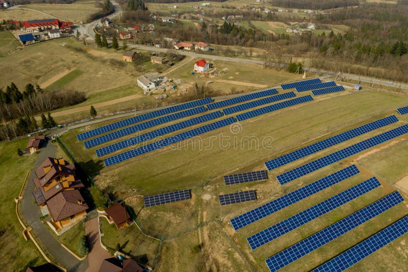 Aerial view of large field of solar photo voltaic panels system producing renewable clean energy on green grass background. Aerial view of large field of solar photo voltaic panels system producing renewable clean energy on green grass background.