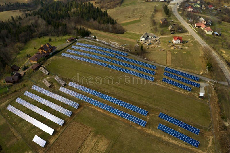 Aerial view of large field of solar photo voltaic panels system producing renewable clean energy on green grass background. Aerial view of large field of solar photo voltaic panels system producing renewable clean energy on green grass background.