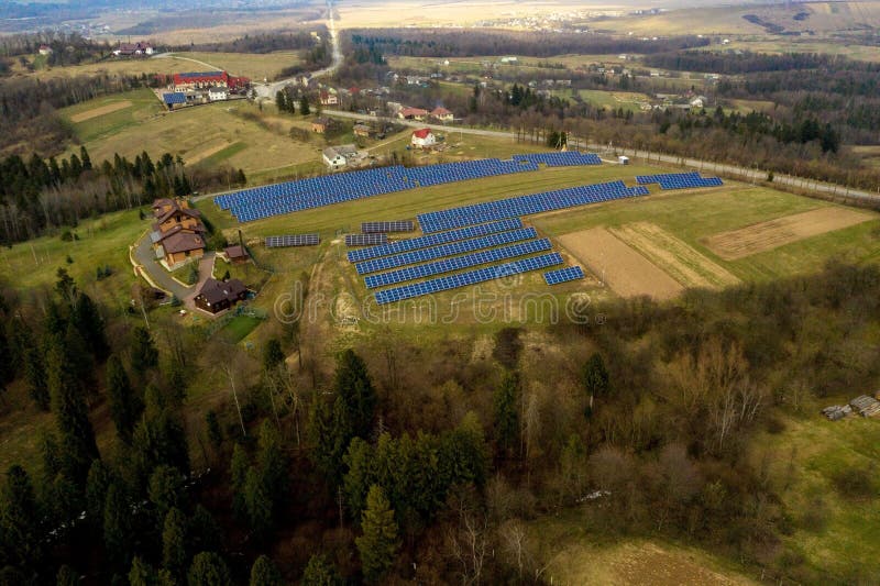 Aerial view of large field of solar photo voltaic panels system producing renewable clean energy on green grass background. Aerial view of large field of solar photo voltaic panels system producing renewable clean energy on green grass background.