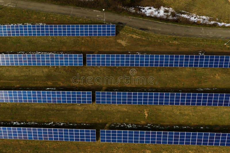 Aerial view of large field of solar photo voltaic panels system producing renewable clean energy on green grass background. Aerial view of large field of solar photo voltaic panels system producing renewable clean energy on green grass background.