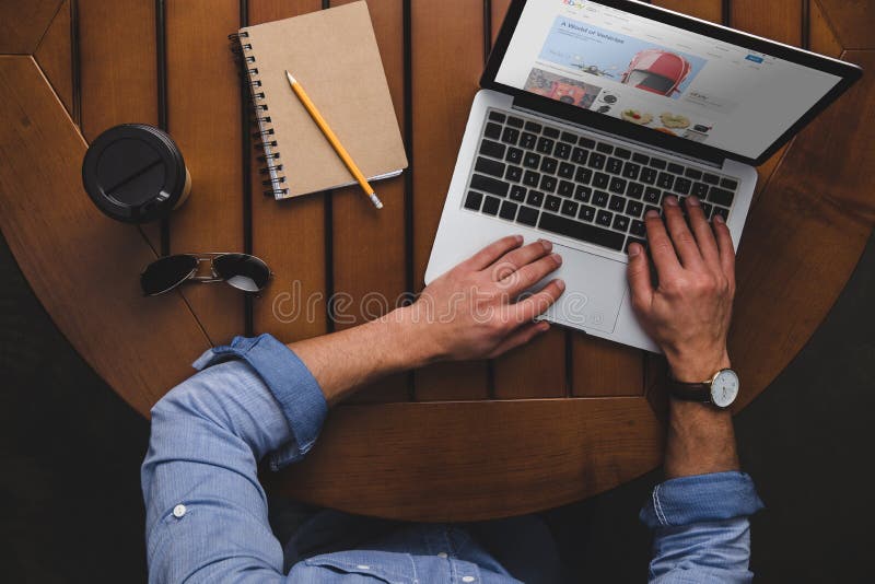 Vue aérienne de l'homme à l'aide de l'ordinateur portable avec le site Web d'ebay tout en se reposant à la table avec du café photos stock