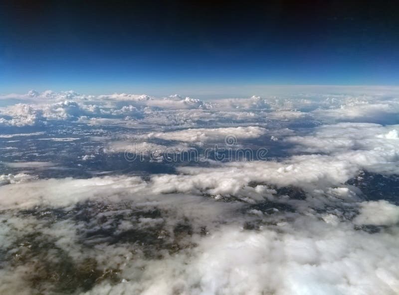 Vue aérienne de la terre de la haute altitude avec le ciel bleu-foncé et des différents types de nuages blancs avec la neige sur