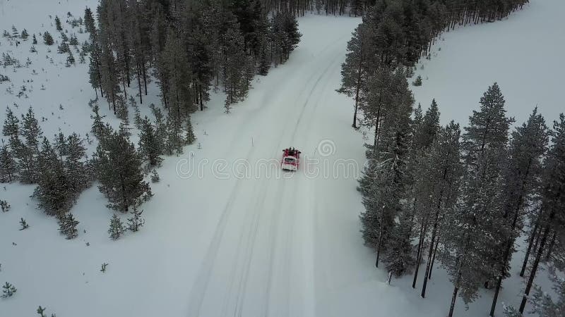 Vue aérienne de la voiture rouge sur la route dans le beau paysage d'hiver de la Laponie pendant chutes de neige Cheminement liné banque de vidéos
