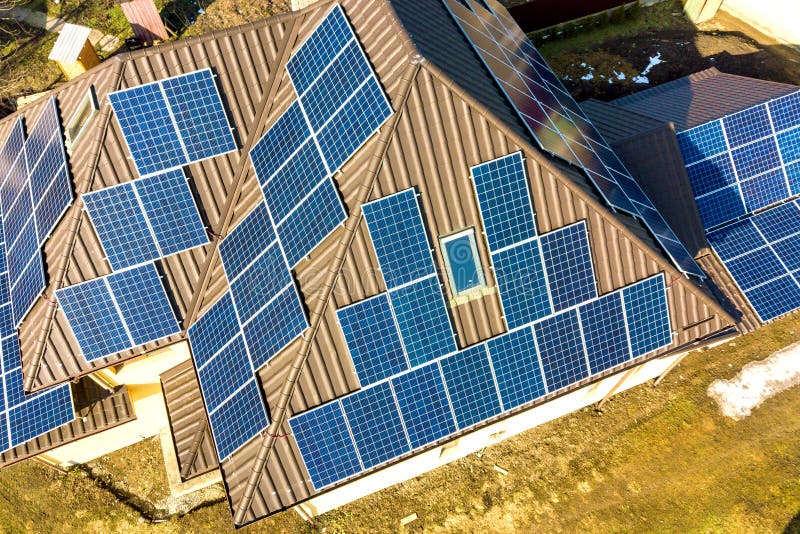 Aerial top view of new modern residential house cottage with blue shiny solar photo voltaic panels system on roof. Renewable ecological green energy production concept. Aerial top view of new modern residential house cottage with blue shiny solar photo voltaic panels system on roof. Renewable ecological green energy production concept.