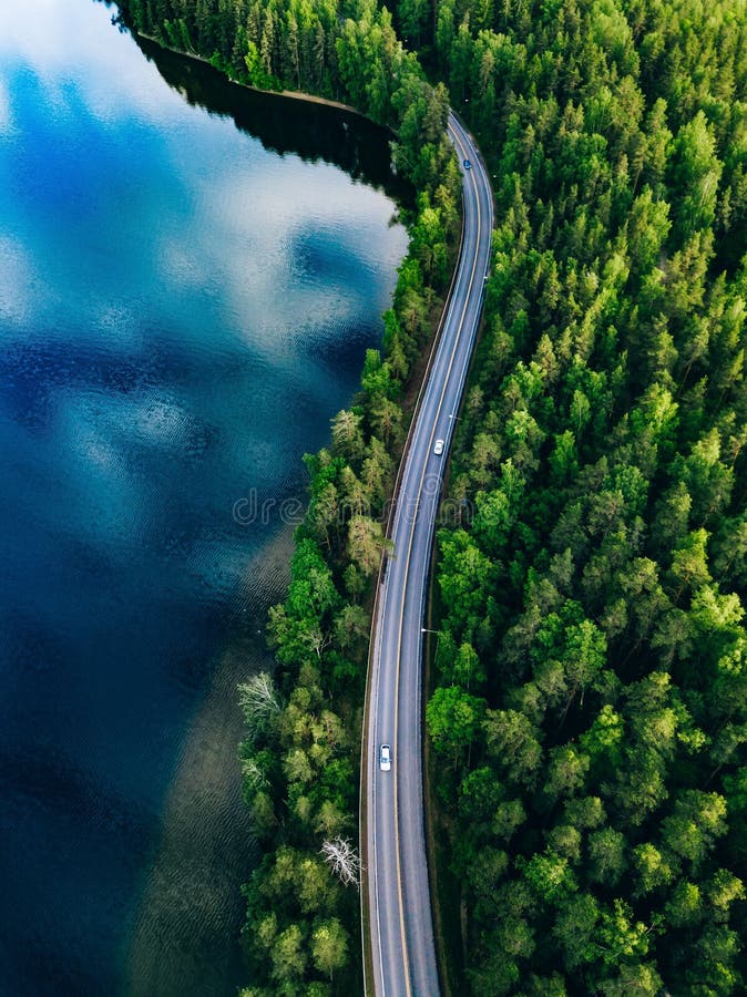 Vue aérienne de route entre la forêt verte et le lac bleu en Finlande image stock
