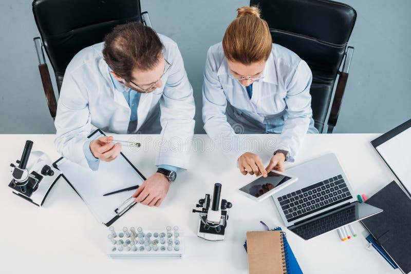Vue aérienne des chercheurs scientifiques dans des manteaux blancs utilisant le comprimé ensemble sur le lieu de travail photographie stock libre de droits