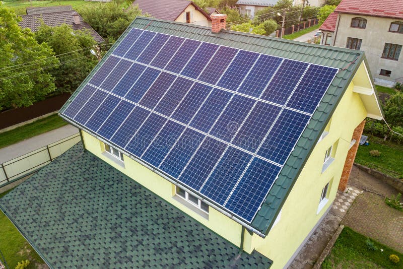 Aerial top view of new modern residential house cottage with blue shiny solar photo voltaic panels system on roof. Renewable ecological green energy production concept. Aerial top view of new modern residential house cottage with blue shiny solar photo voltaic panels system on roof. Renewable ecological green energy production concept.