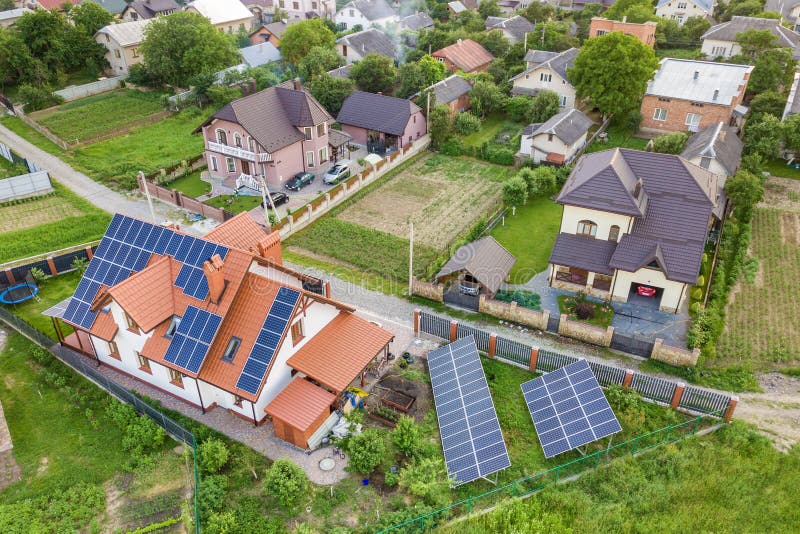Aerial top view of new modern residential house cottage with blue shiny solar photo voltaic panels system on roof. Renewable ecological green energy production concept. Aerial top view of new modern residential house cottage with blue shiny solar photo voltaic panels system on roof. Renewable ecological green energy production concept.