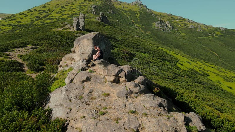 Vue aérienne un jeune athlète masculin assis au bord d'une falaise et regardant au loin. regarder vers l'avenir banque de vidéos