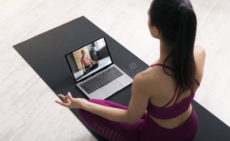 Vue ci-dessus la jeune femme faisant des exercices de respiration ou de méditation suite à un tutoriel vidéo sur ordinateur portab photo libre de droits