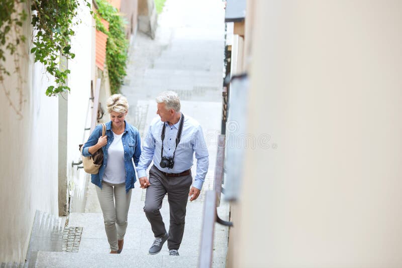 Vue courbe des couples d'une cinquantaine d'années tenant des mains tout en s'élevant fait un pas dehors photographie stock libre de droits Vue courbe des couples d'une cinquantaine d'années tenant des mains tout en s'élevant fait un pas dehors photographie stock libre de droits