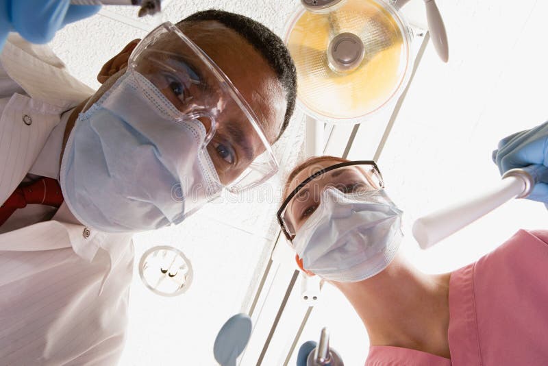 Vue d'angle faible de dentiste et d'infirmière dentaire images libres de droits Vue d'angle faible de dentiste et d'infirmière dentaire images libres de droits